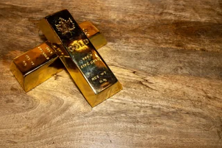 Two solid gold bars on a wooden surface