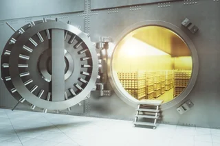 Open bank vault with golden walls and gold stacks